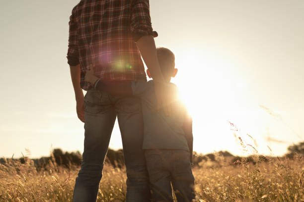 istock Father and son watching into a distance at sunset time. 2189245936