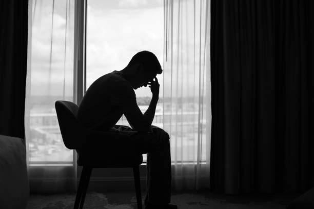 istock Sad lonely man sitting in the dark room. 2189246711
