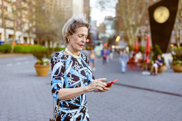 istock Elderly Woman Using Smartphone in Busy Urban Park 2189247732