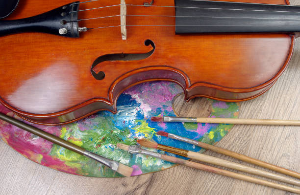 istock violin, brushes and palette on a wooden background. top view. 2189251226