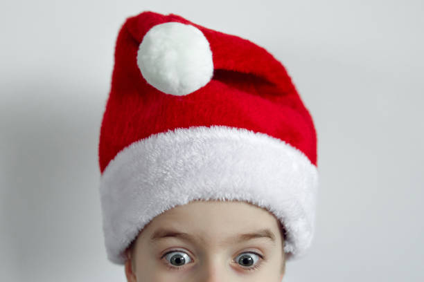 Close-up of a cheerful young boy with a hat and backpack in a natural outdoor setting. The image captures a moment of childhood joy, adventure, and curiosity in a forest environment.