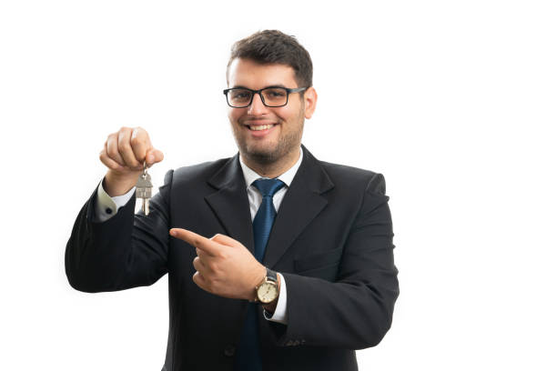 istock Real estate agent with friendly expression pointing house keys 2189255674