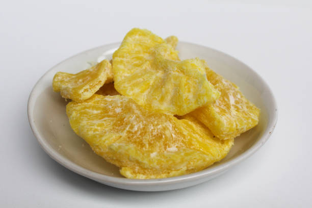 istock Dried pineapple sweets. Candied and dried pineapple. On small white plate. Isolated on white background 2189258175