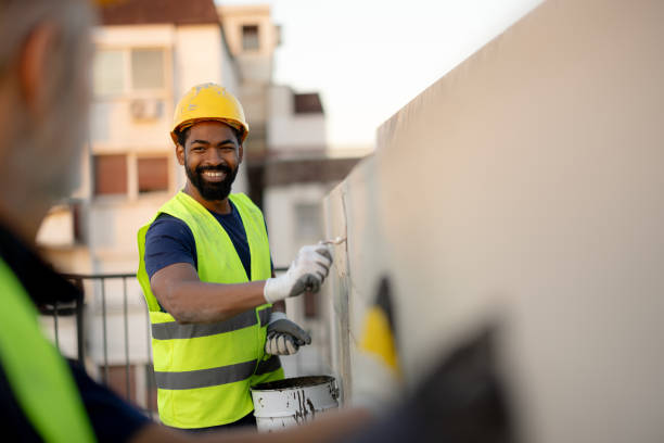 istock Smiling Construction Worker Painting a Wall on a Sunny Day 2189260373