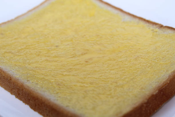 One slice of white square bread, with margarine spread, on white plate, isolated on white background