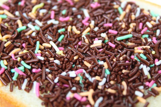 One slice of white square bread, with colorful chocolate sprinkles spread, on white plate, isolated on white background