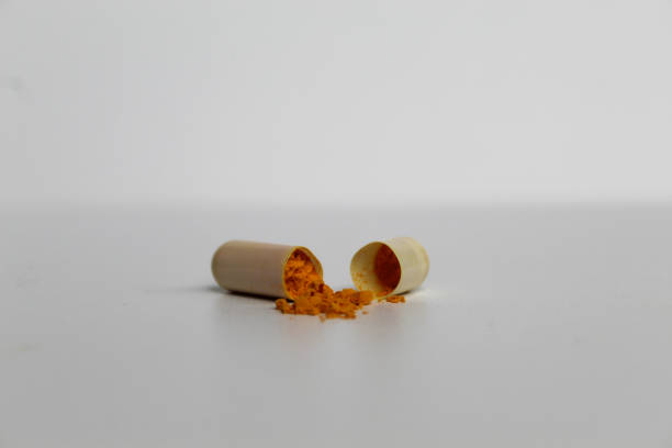 istock Opened capsule with yellow turmeric powder filling inside. Isolated on white background 2189261256