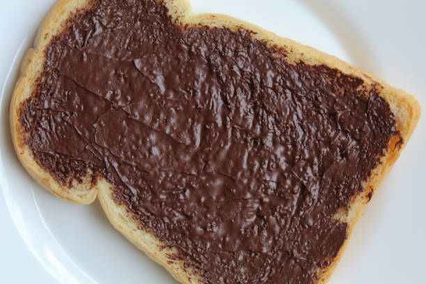 istock One slice of white bread, covered by chocolate spread, on white plate, isolated on white background. Prepare chocolate sandwich. Flat lay or top view 2189261493
