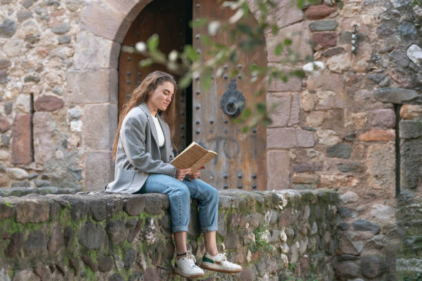 istock Young woman reading on a stone wall at a historic castle. 2189261547