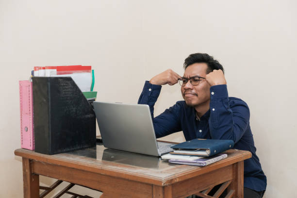 istock Stressed and tired Southeast Asian Man Working While Sitting In Front Of Laptop In Home Office 2189262376