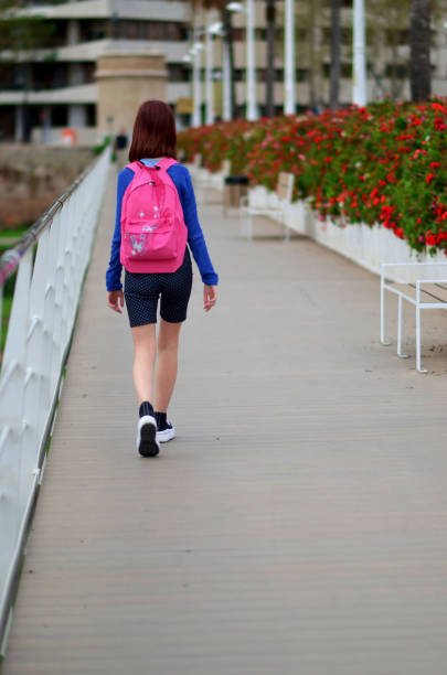 Side View Portrait Of Schoolgirl Carrying Black Backpack Against White Background