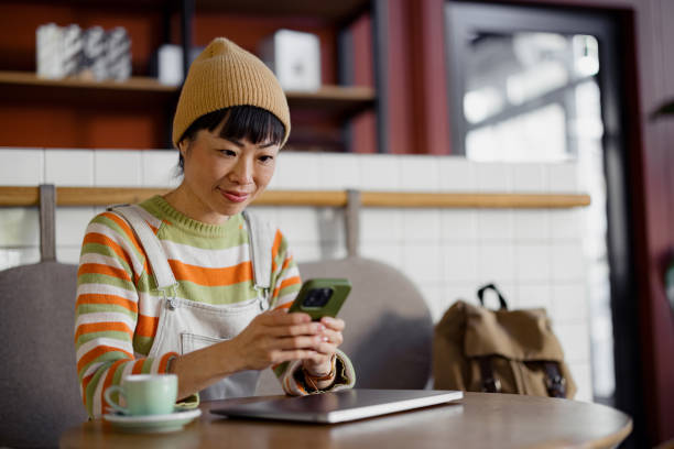 istock Woman Working at Cozy Coffee Shop Using Smartphone and Laptop 2189267015