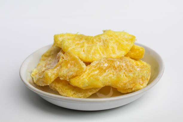 istock Dried pineapple sweets. Candied and dried pineapple. On small white plate. Isolated on white background 2189267100