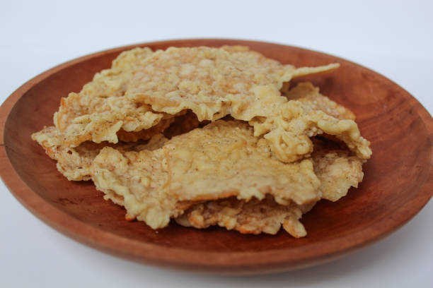 istock Keripik tempe or tempeh crackers, square shape. Thin slices tempeh, fried with flour dough. On wooden plate, isolated in white background 2189267940