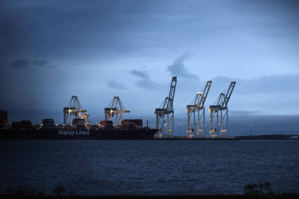 Delta, Canada - December 7, 2024: Morning view from the Tsawwassen Ferry Terminal to GCT Deltaport on Roberts Bank Way, Tsawwassen. A Hapag-Lloyd freight ship is docked. Sunrise in autumn.