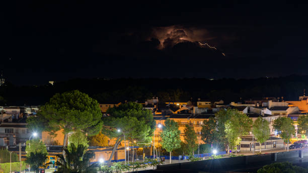 As the summer rain falls, a thunderhead blows eastward sending numerous  lightning strikes out over southwest suburban Denver homes.