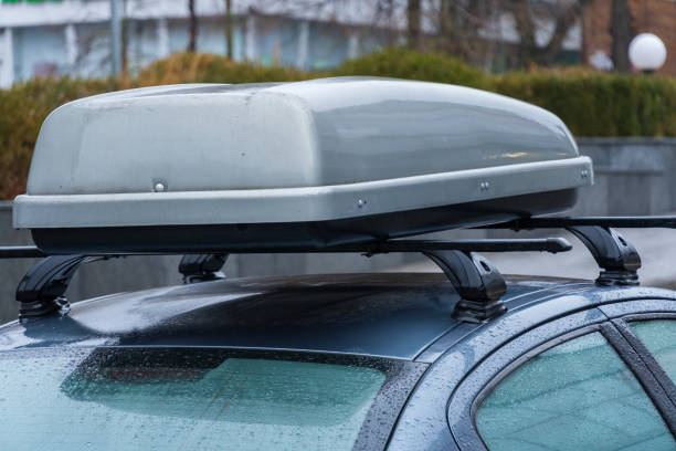 istock A modern black vehicle is parked under cloudy skies with light rain falling, showcasing a streamlined rooftop cargo box designed for extra storage. Surrounding greenery adds to the urban atmosphere 2189270350