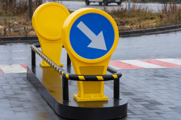istock A bright yellow directional sign with a blue circular background and white arrow points left in a rainy urban setting. The sign is placed on a pedestrian crossing area made of black paving stones 2189270377