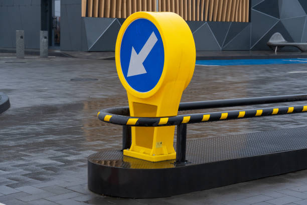 istock A bold yellow directional sign with a blue circular background indicating leftward movement stands on a sleek pavement in an urban setting. The surroundings showcase contemporary architecture 2189270384
