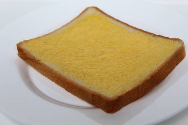 One slice of white square bread, with margarine spread, on white plate, isolated on white background