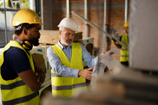istock Construction Workers Reviewing Blueprints on Site in Safety Gear 2189271605