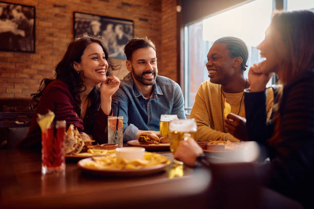 istock Multiracial group of happy friends talking while sitting in a pub. 2189273772