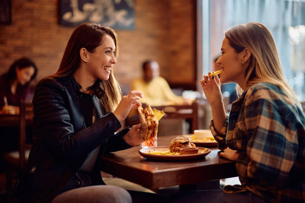 istock Young happy women talking while eating in a pub. 2189273921
