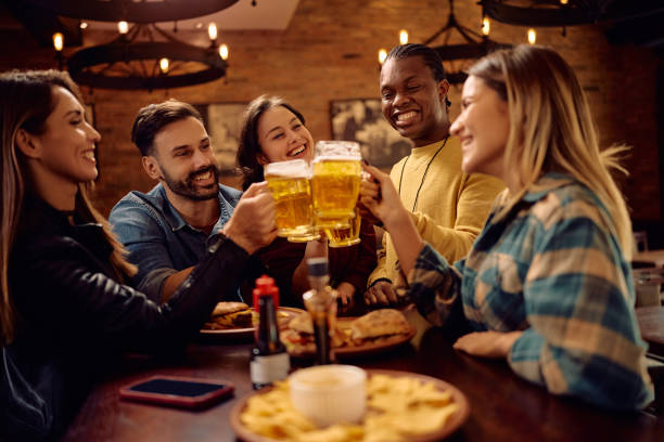 istock Multiracial group of happy friends having fun and toasting while drinking beer in a pub. 2189274660