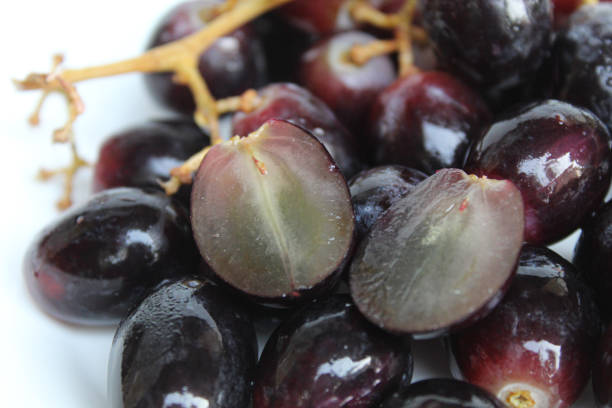 istock Halved dark purple or black grape with stem, seedless grape fruit, on white background 2189275258