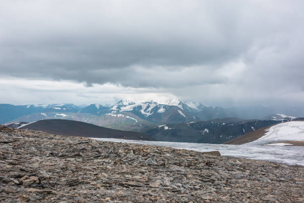 istock Dramatic panoramic view from big glacier to wide alpine valley and large snow-capped mountain range in rainy low clouds. Awesome vast landscape with high snowy mountains in rain under gray cloudy sky. 2189278086