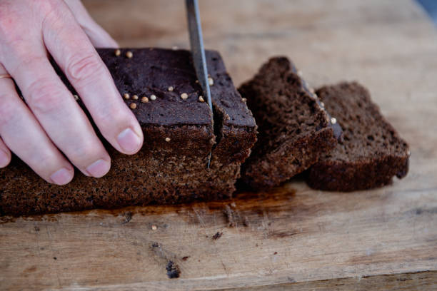 istock The man cuts whole-wheat rye bread on a wooden cutting board. 2189278470