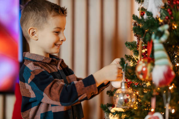 istock Young boy decorating christmas tree with christmas ornaments at home. 2189286462