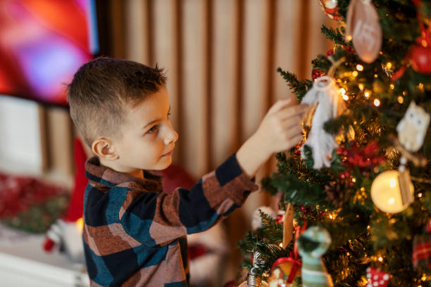 istock A cute little boy decorating christmas tree at home. 2189291836