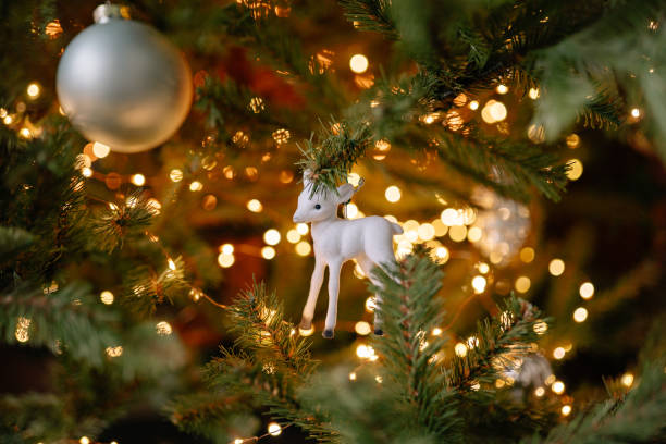 istock Festive decorations on a Christmas tree with twinkling lights and a white reindeer ornament 2189295459
