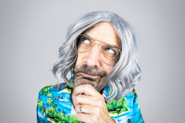 A funny fisheye image of an older gray guy with long hair with his chin in his hand as he thinks about something.