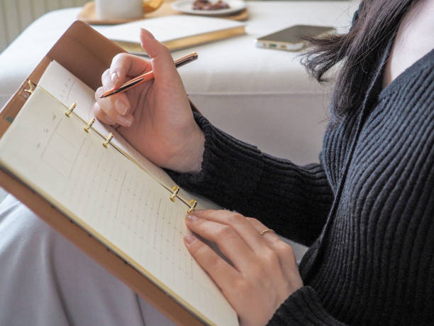 istock Woman sitting in a bright room with an open notebook, taking notes 2189298037