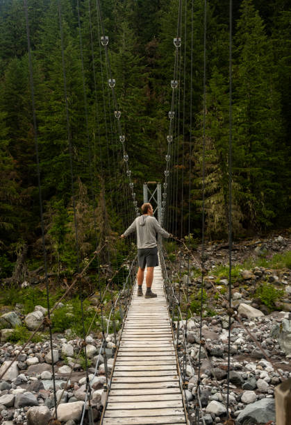 istock Man Pauses on Carbon River Suspension Bridge 2189299176