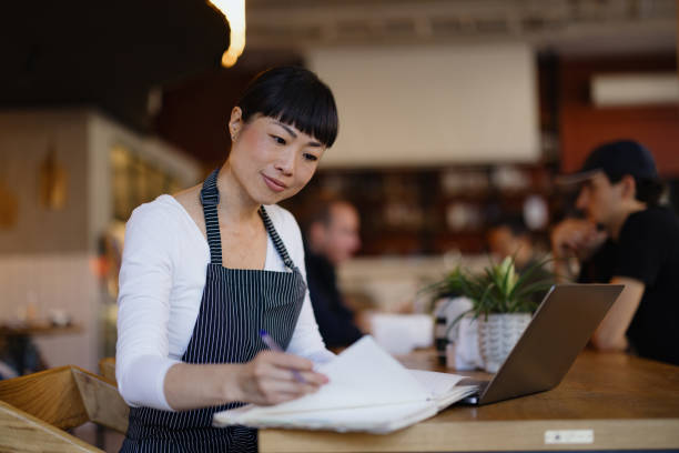 istock Focused Cafe Worker Writing Notes in a Cozy Coffee Shop 2189302192