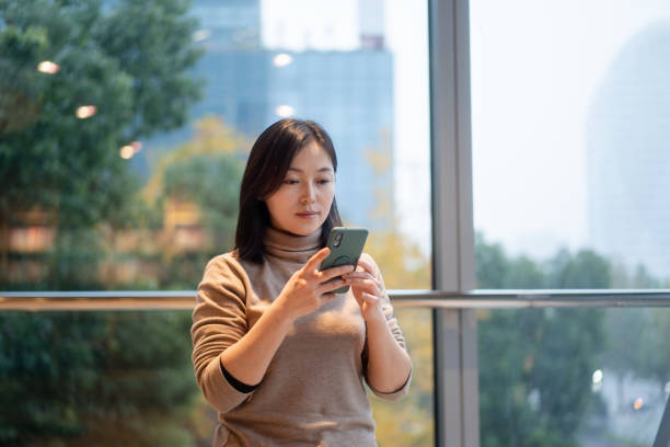 istock female with smart phone in modern office beside window 2189306665