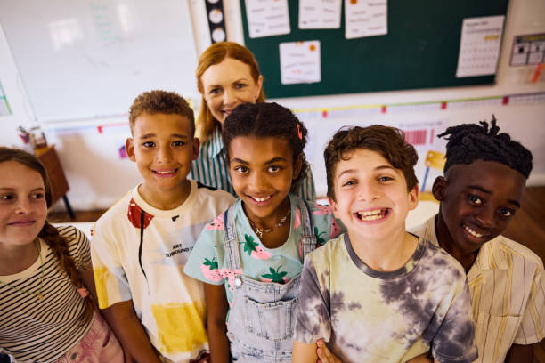 istock Diverse group of elementary school students smiling with their teacher in classroom 2189309926