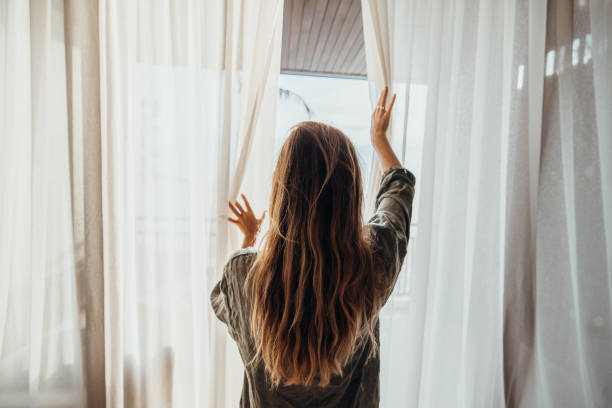 istock Woman Opening Curtains to Balcony with Ocean View 2189314038