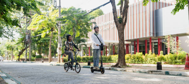 Commuting to work with bicycle. Young business person cycling and riding electric scooter to office in downtown district. Modern diversity people use eco transportation in city. Sustainable lifestyle.