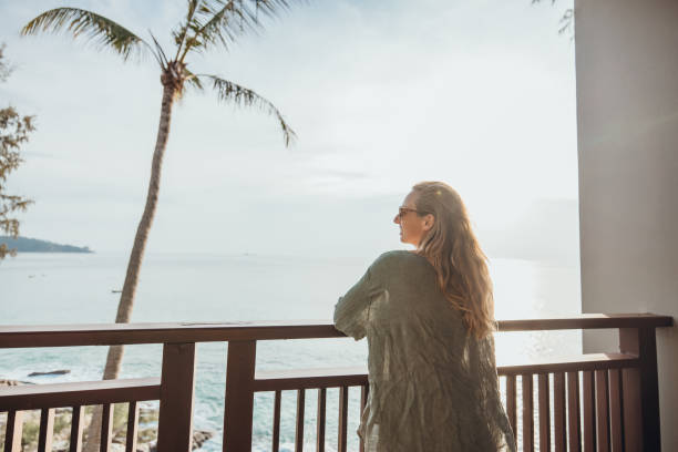 istock Woman Relaxing on Balcony Overlooking Ocean at Sunset 2189314335