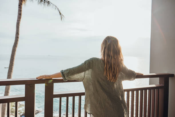 istock Woman Relaxing on Balcony Overlooking Ocean at Sunset 2189314379