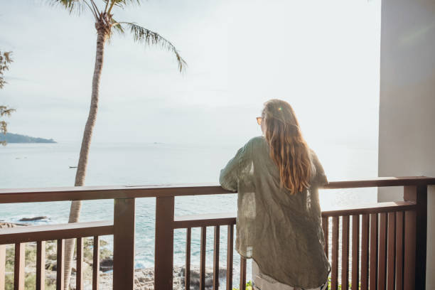 istock Woman Relaxing on Balcony Overlooking Ocean at Sunset 2189314398