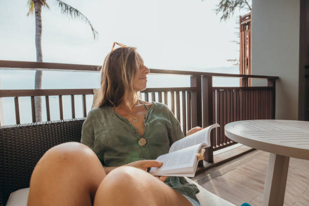 istock Woman Relaxing on Balcony Reading a Book 2189314560