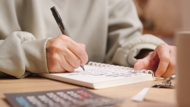 istock Close up human hand writing New year Resolutions Plans on white paper notebook planning Goal List for well being ,Beginning the new life and enjoy life 2189316314