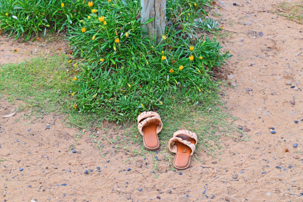 A pair of sandal's left at the beach near a post