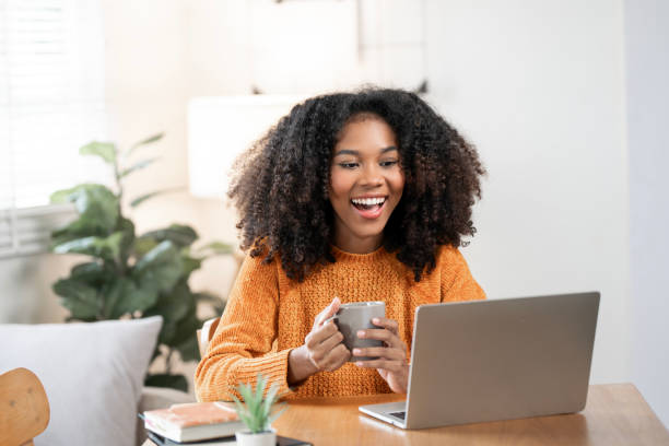istock Happy black woman enjoying morning coffee while using laptop at home. 2189321237