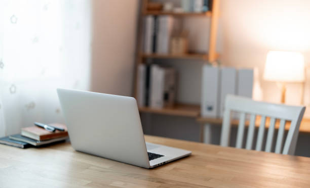 istock Close up view of simple workspace with laptop, notebooks, on wooden table with blurred office room background 2189321884